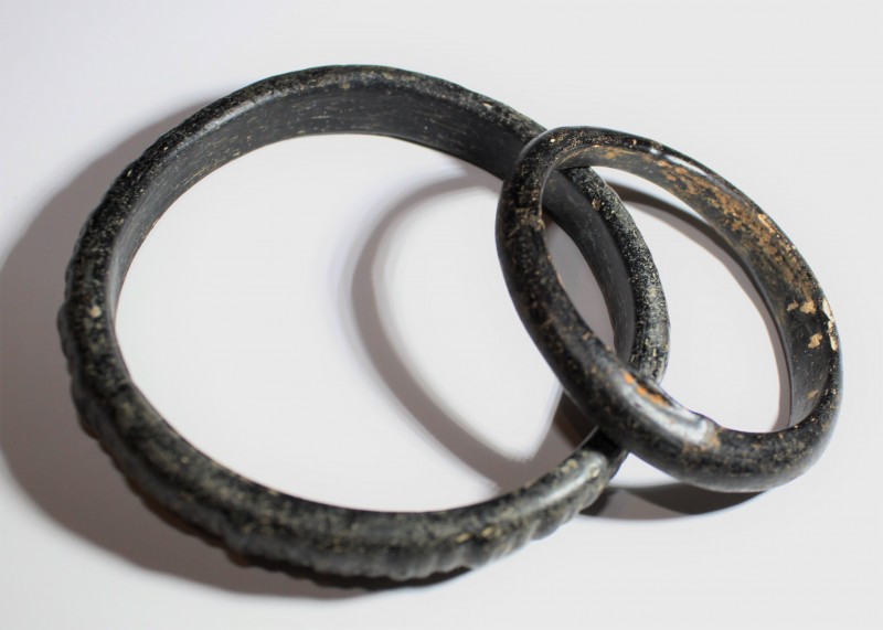 1st - 2nd century AD. A pair of black and grey glass bracelet, one with ribbed d...