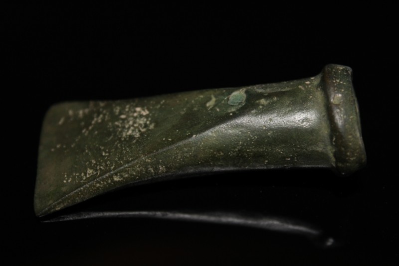 1st millenium BC. A small bronze axe head with sharply curving blace, reinforcin...