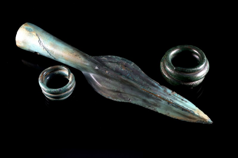 Late Iron Age, Bronze spear-head and two spiral rings. 1200-800 BC. Dark green p...