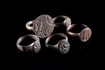 Lot of 5 Roman Bronze Finger Rings, c. 3rd-5th century AD. Various shaped bezels engraved with floral and geometric patterns. All intact.