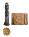 A BRONZE CYLINDER SEAL WITH A SCHEMATIC PAZUZU HEAD HANDLE Iron Age II, 7th-6th century BCE. 40.9 mm high with the suspension loop. Depicting a worshi...