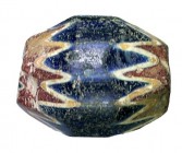 A LARGE BARREL-SHAPED BLUE WITH WHITE AND RED GLASS BEAD Ca. 15th century CE. 4.4 cm wide, 3.4 cm in diameter. Longwise perforated. In good condition....
