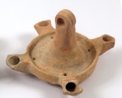 A HERODIAN TERRACOTTA OIL LAMP WITH 4 NOZZLES 1st century CE. 17.4 cm in diameter, 10.8 cm high. 2 nozzles are partly restored and the hanging handle ...