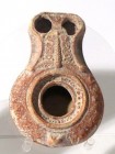 A BEIT-NATIF TYPE CLAY OIL LAMP WITH TWO NOZZLES 4th century CE. 9.5 cm. Decorated with 3 branches and schematic motifs. In very good condition. Ex Ju...