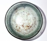 A TRANSLUCENT GLASS RIBBED BOWL Early Roman Period, 1st century CE. 17.6 cm in diameter. In perfect condition. Ex Yoav Sasson collection, Jerusalem.