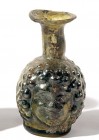 AN OLIVE-GREEN GLASS JANUS-HEAD FLASK Roman Period, ca. 4th century CE. 8.0 cm high. A small missing rim fragment is restored but in good condition. E...