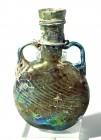A GLASS PILGRIM FLASK Byzantine Period, 4th-5th century CE. 13.5 cm high. With nice patina. Mended in the middle but in fair condition. Ex Abraham Ros...