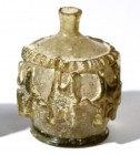 A YELLOW GLASS PERFUME BOTTLE Umayyad Period, 7th-8th century CE. The globular body is decorated with six applied stars and a wavy band around the sho...