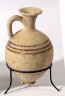 A CHOCOLATE-ON-WHITE TERRACOTTA JUGLET Late Bronze Age, 1550 – 1200 BCE. 15.3 cm high. A minor chip at the rim but in very good condition.