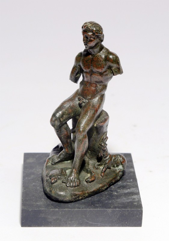 A BRONZE FIGURINE OF A NAKED YOUTH SEATED AND SURROUNDED BY ANIMALS Roman Period...