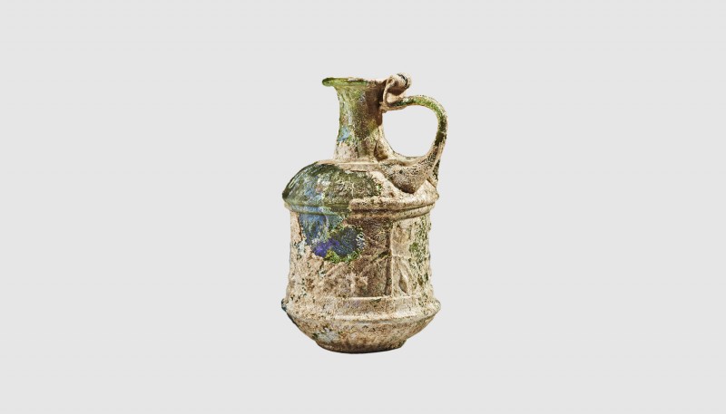 A Roman yellow-green glass jug. First half of the 1st century AD. 9.50cm high. F...