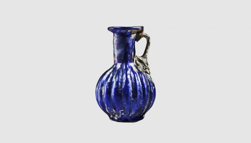A Roman blue ribbed glass jug. Second half of the 1st century AD. 7.9cm high. Fr...
