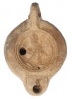 ROMA. Imperio Romano. Lucerna (II-III d.C.). Terracota. Figura masculina coronada avanzando hacia der. En la base un sello y epígrafe. Longitud 10,2 c...