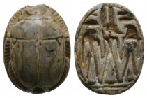 New Kingdom, c. 1550-1075 B.C. Steatite scarab (19x14mm). Base engraved with the god Amun standing between Horus and another deity, perhaps Ra. Intact...