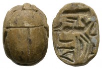 New Kingdom, c. 1550-1075 B.C. Steatite scarab (16x11mm). Base engraved with the pharaoh kneeling in front of pillar/obelisk, preceded by ‘may he give...