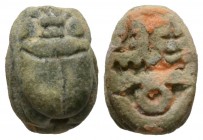 Late Period, c.1075-650 B.C. Green paste (?) scarab (16x11mm). Base engraved with crude signs. Intact, although worn, pierced for mounting, some orang...