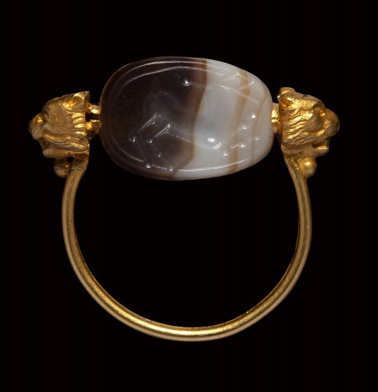 An etruscan banded agate scarab intaglio mounted on an gold ring. Horned stag ru...