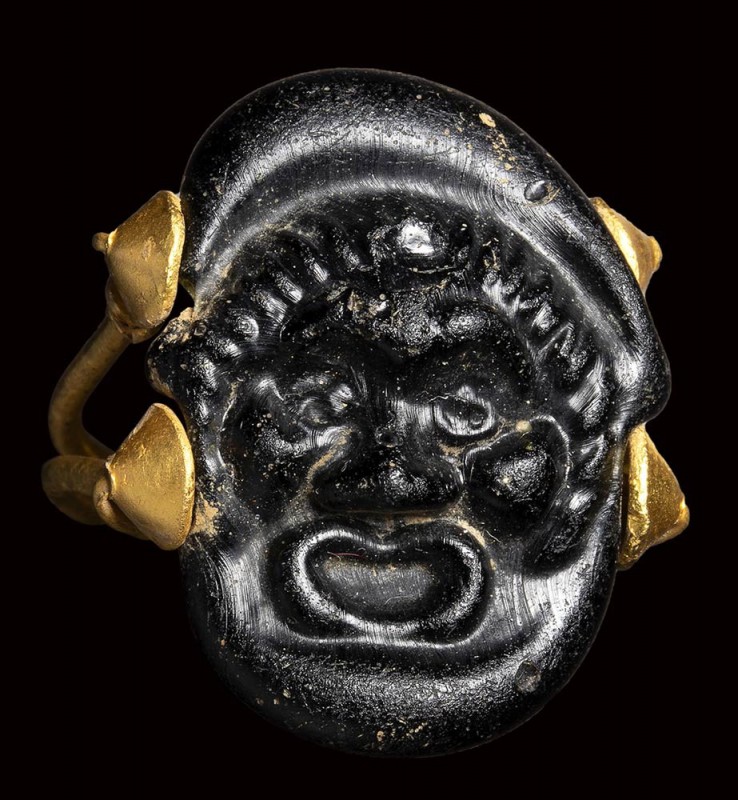 A rare roman black glass cameo set in an ancient gold ring. Theatrical mask. 
...