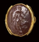 A postclassical carnelian intaglio set in a gold revival ring. Female figure with torch.