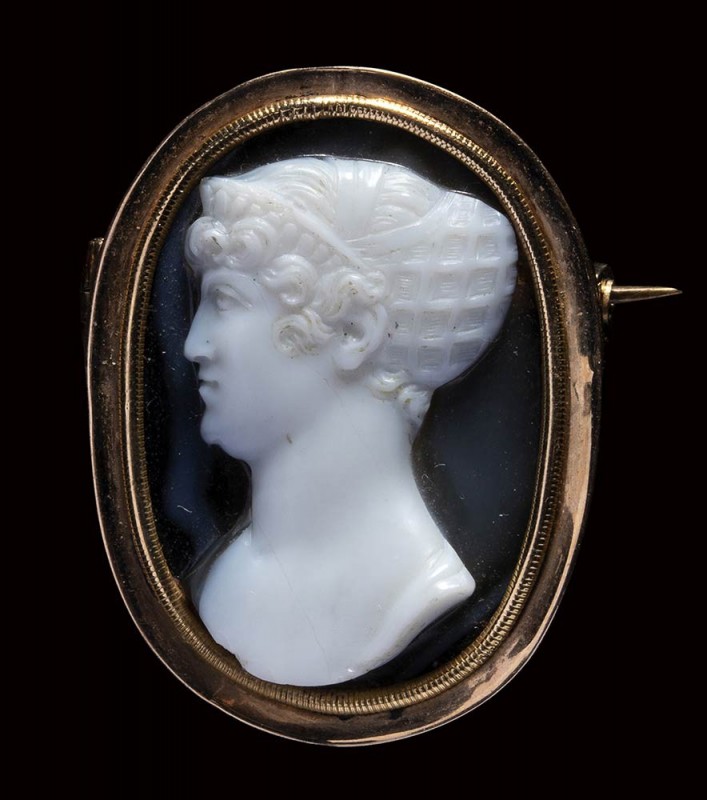 A late Georgian gold brooch set with an onyx cameo portrait by Berini. Bust of a...