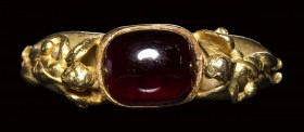A modern gold ring with a garnet stone.