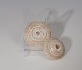 PRÓXIMO ORIENTE. Mesopotamia. Par de fusayolas (3000-2000 a.C.). Alabastro. Con perforaciones central. Diámetro 3,1 y 3,9 cm.