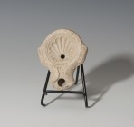 ROMA. Imperio Romano. Lucerna (I-II d.C.). Terracota. Con decoración de concha en disco central y un agujero de llenado. Longitud 9,8 cm.