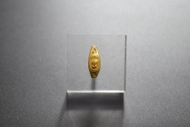 Gold finger ring. 2nd-4th cent. AD. (3.20g.). Band decorated and raised shield decorated with facing male head. Minor bended band, otherwise almost in...