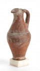 OINOCHOE FENICIO-PUNICA
 Prima metà del V secolo a.C.; alt cm 17,5 (con base cm 19); Rara, con ingobbio rosso e la caratteristica decorazione a linee...