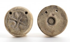 COPPIA DI PESI DA TELAIO
 IV - II secolo a.C.; diam. l’uno cm 7,5; alt. l’uno cm 2; Decorati da motivi a stella e a rosetta. Con due fori di sospensi...