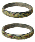 A lovely Roman/Byzantine glass bangle, c. 4th - 7th Century A.D. in opaque black glass with yellow, red, and green marbling. Dia: 2 3/8 in. (6 cm). Re...