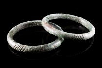 Bronze Age, Pair of Bronze Penannular Bracelets, c. 9th-6th century BC (7.6cm), with vertical bands decoration. Green patina, intact.