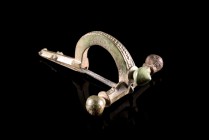 Roman Bronze Crossbow Fibula, 3rd-4th century AD (5.4cm). Brooch with three knobs, decorated with chain pattern. Green patina, intact with pin.