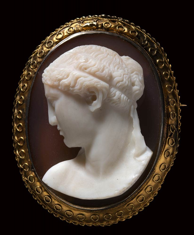 A two-layered agate cameo mounted on a gold brooch. Female bust. 

19th centur...