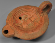 ARQUEOLOGÍA. ROMA. Imperio Romano. Lucerna (ss. I-III d.C.), decorada con un jarrón con pavos reales en ambos lados. Terracota. Longitud 10 cm.