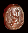 An early classical greek carnelian scaraboid intaglio. A seated griffin.