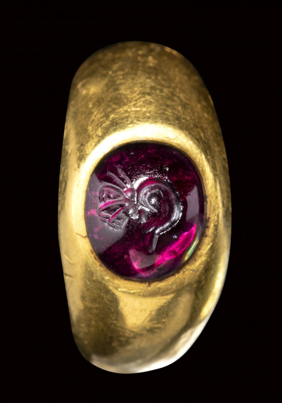 A roman gold ring set with a garnet cabochon intaglio. Butterfly metamorphosis....