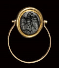 A roman dark glass paste intaglio set in a gold swivel ring. Eagle.