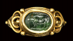 A roman green chalcedony intaglio set in a gold ring. Heafer under a tree.
