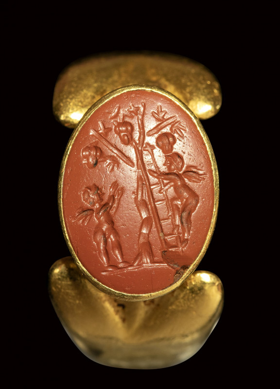 A fine roman red jasper intaglio set in a gold ring. Grape harvest scene with Er...