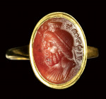 A fine roman carnelian intaglio mounted in a modern gold ring. Bust of Serapis with greek inscriptions.