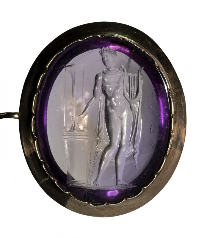 A fine amethyst neoclassical intaglio set in a gold brooch. Apollo playing lyra....