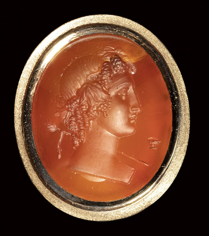 A neoclassical carnelian intaglio set in a modern ring. Bust of a Bacchante. 
...