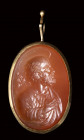 A neoclassical carnelian intaglio set in a gold devotional pendant. Bust of Saint.