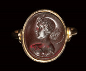 A dark red glass intaglio set in a gold ring. Bust of Diana.
