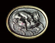 A dark purple glass impression set in a signet gold ring. Lion with an horse.
