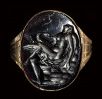 A dark glass Tassie impression set in a gold ring. Leda and the Swan.