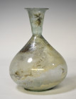 ROMA. Imperio Romano. Botella globular (ss. II-IV d.C.), con cuello troncocónico y boca exvasada. Vidrio. Presenta irisaciones. Altura 17,5 cm.
