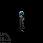 Egyptian Glazed Figural Amulet. Third Intermediate Period, 1069-702 B.C. A blue-glazed male figure standing right, wearing a bag wig and holding a rib...