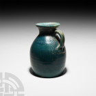 Parthian Blue Glazed Jug. 3rd century B.C.-2nd century A.D. A glazed vessel with piriform body, broad everted rim and m-section handle. 1.4 kg, 21.8 c...